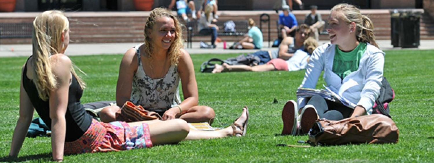 Students sitting in the grass on the quad at CU Boulder