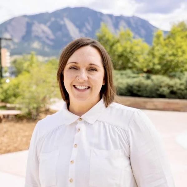 Hannah Wilks in white button up shirt in front of the flatiron mountains and trees