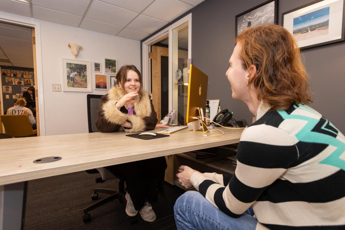 Two students sitting talking at a desk