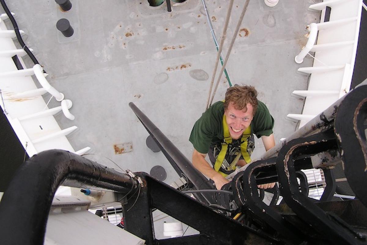 Researcher climbing up a ship out on the ocean.
