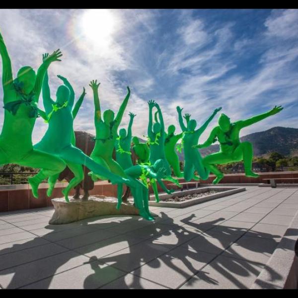 Several people in green suits jumping in the air