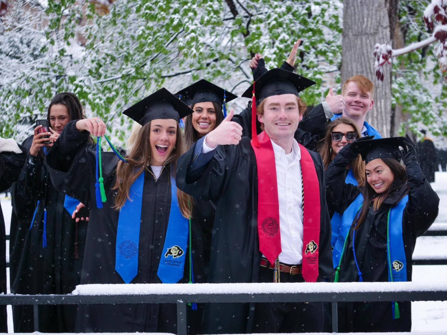 graduating students give a thumbs up at commencement