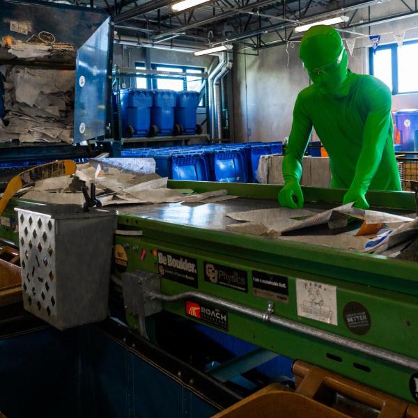 Person in a green suit in the recycling and operations center on campus