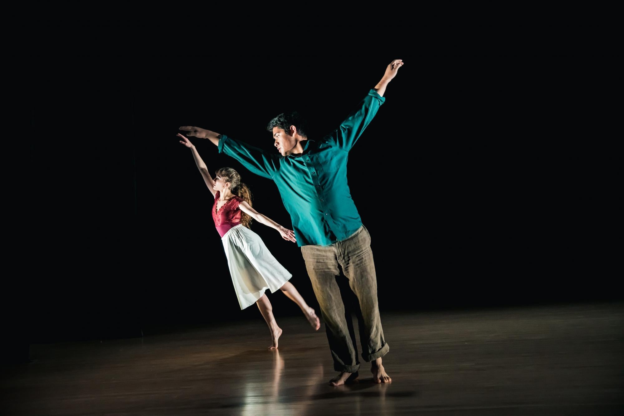 One male dancer leans to the left while a female dancer moves behind him