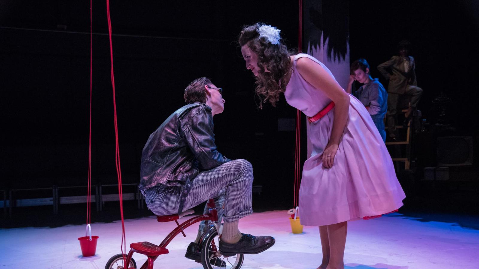 A woman talks to a man on a tricycle