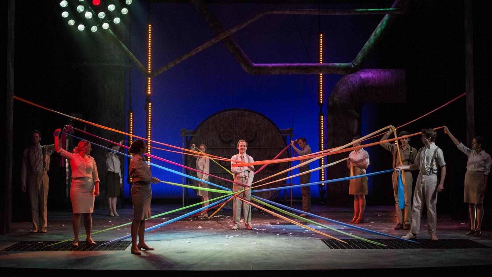 A student actor is wrapped in ribbons held by other actors