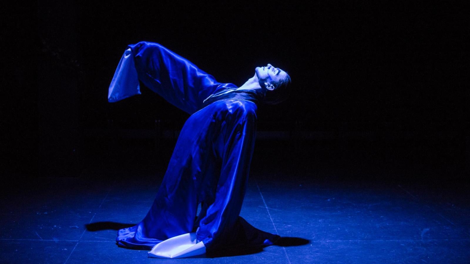 An actor kneels while reaching up