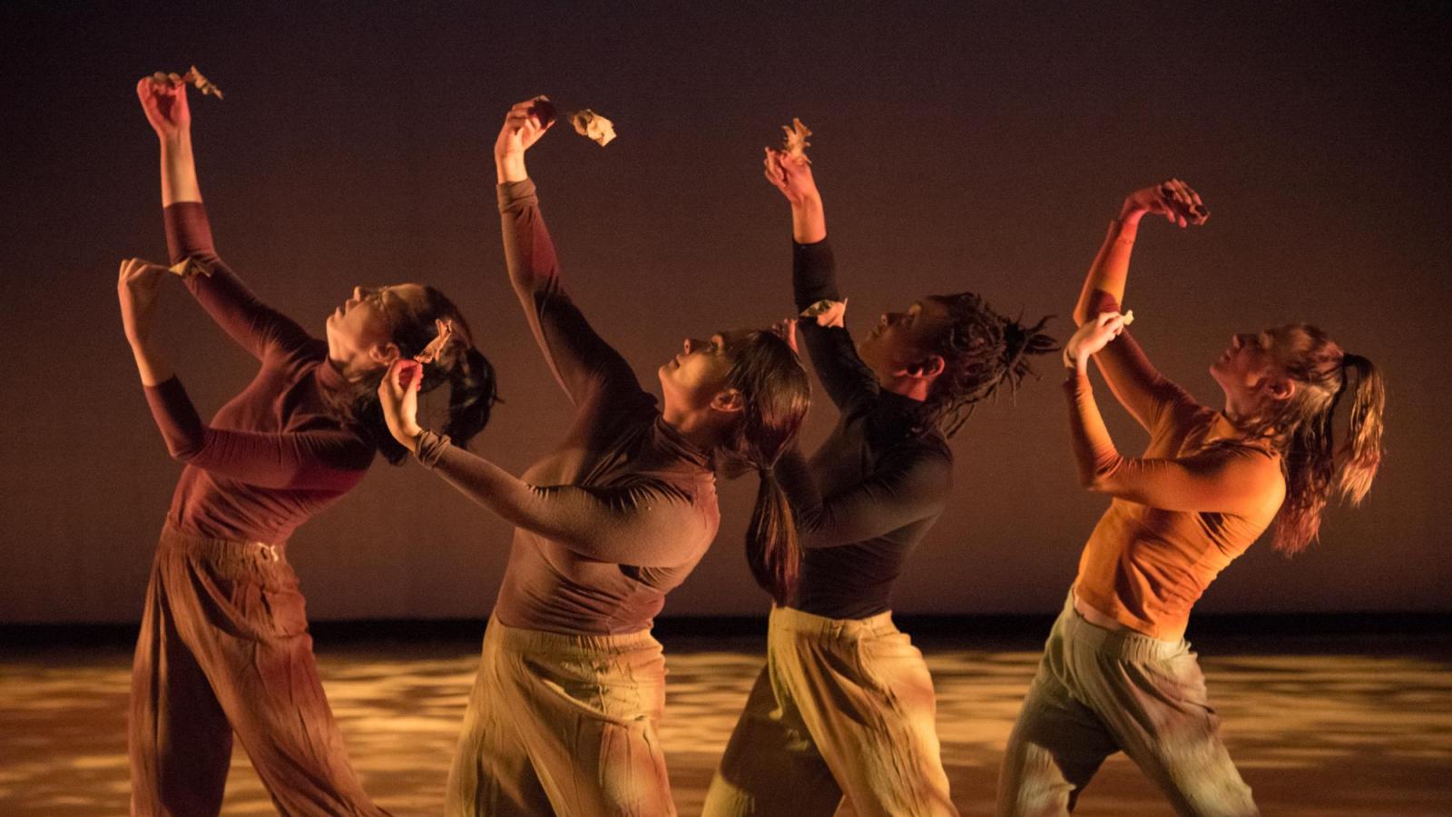 Four dancers hold up leaves