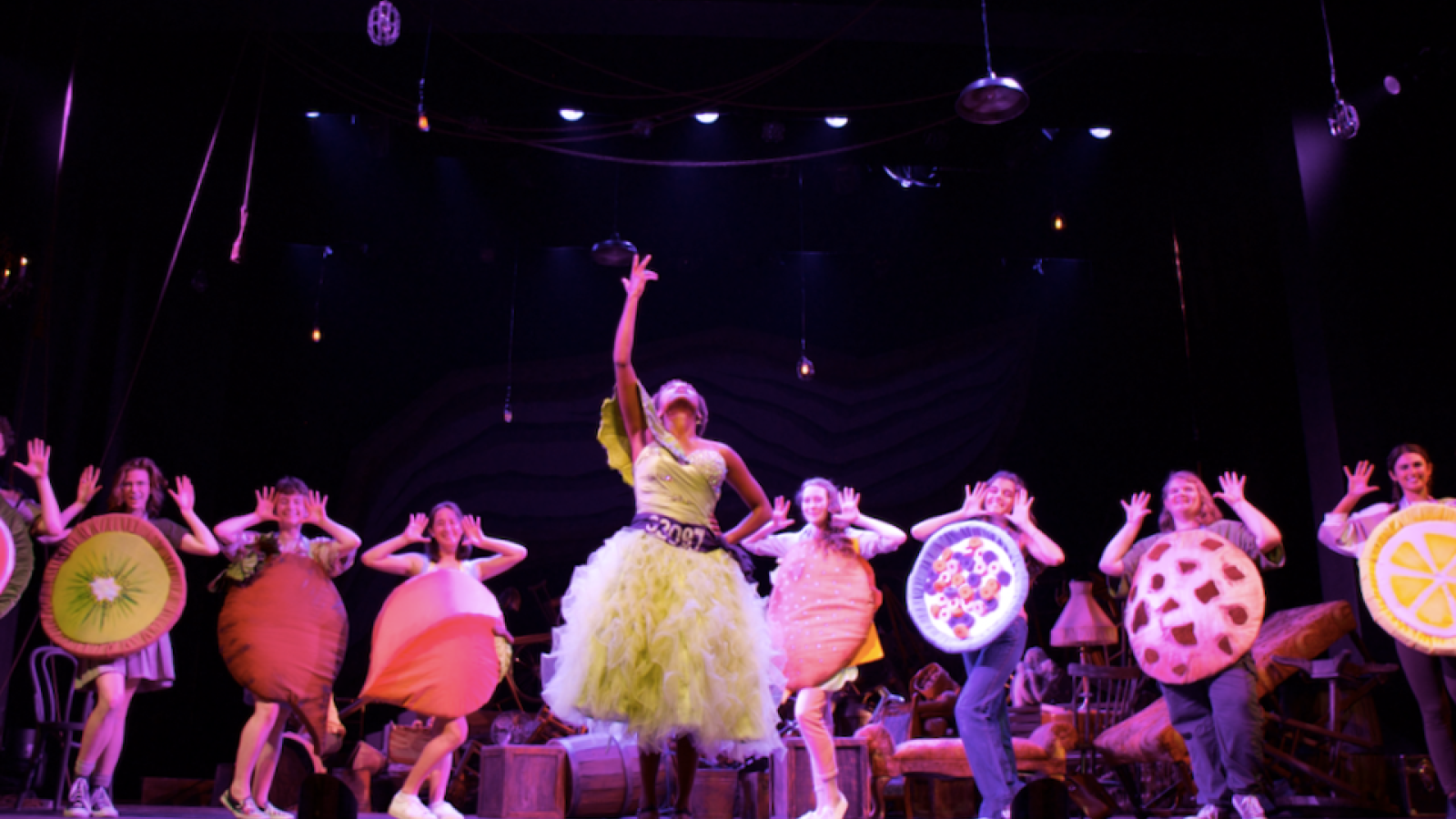 climate cabaret: lead singer gestures triumphantly to the sky while actors dressed as foods surround them