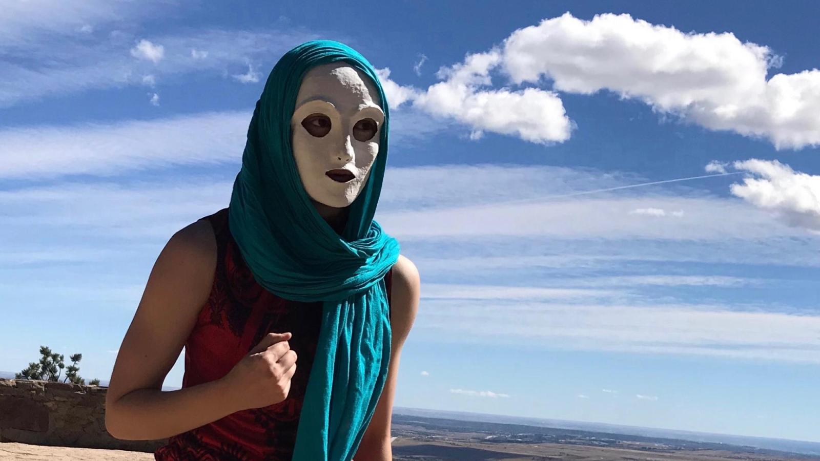A masked performer runs on a mountaintop