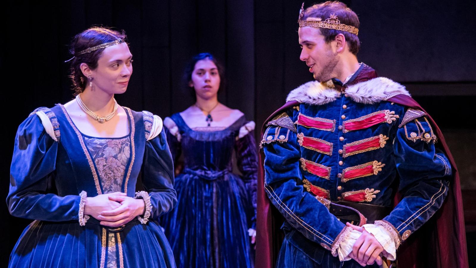 Two student actors look speak which a third looks on from behind