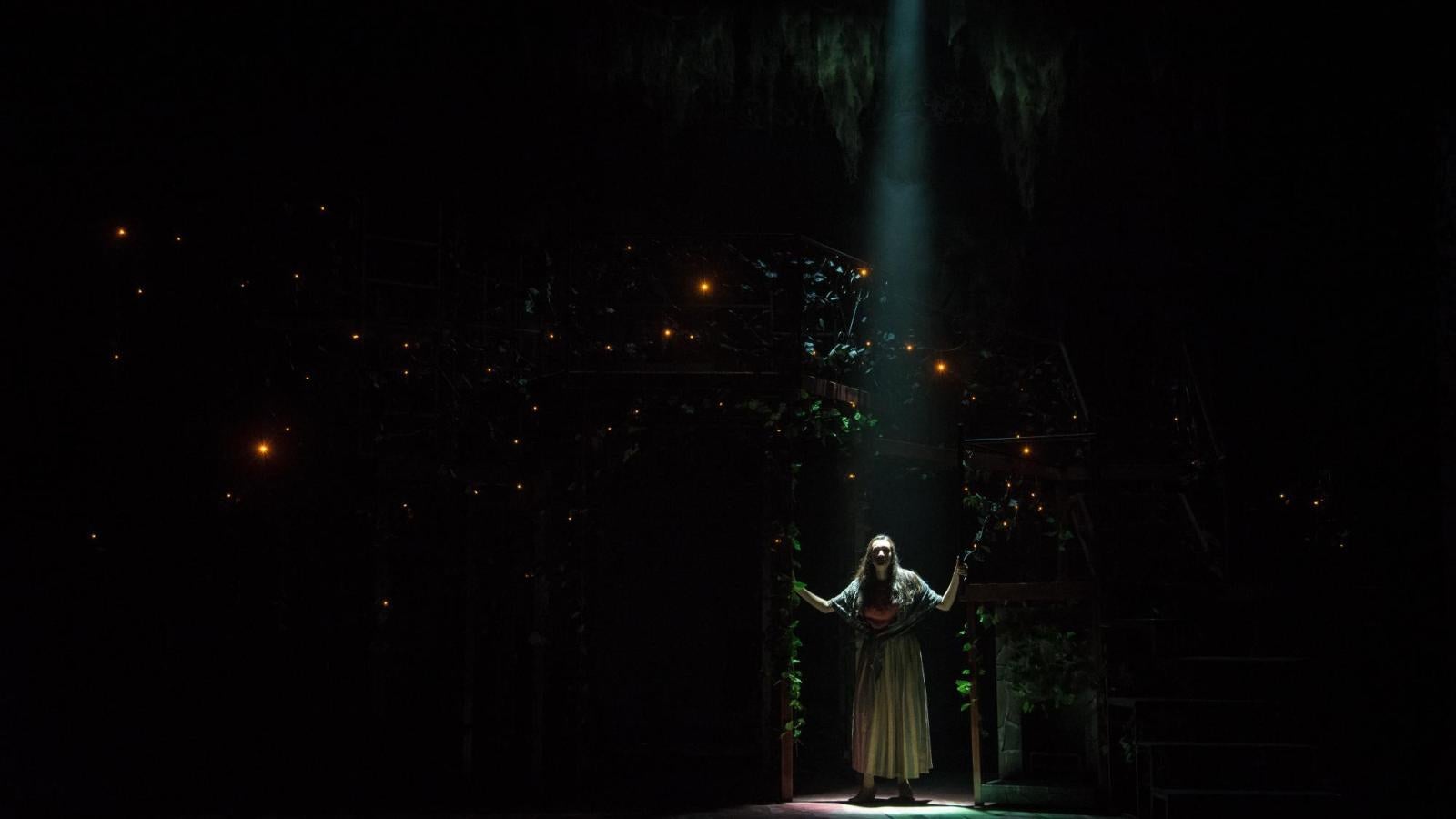 a solo actor enters a dark stage