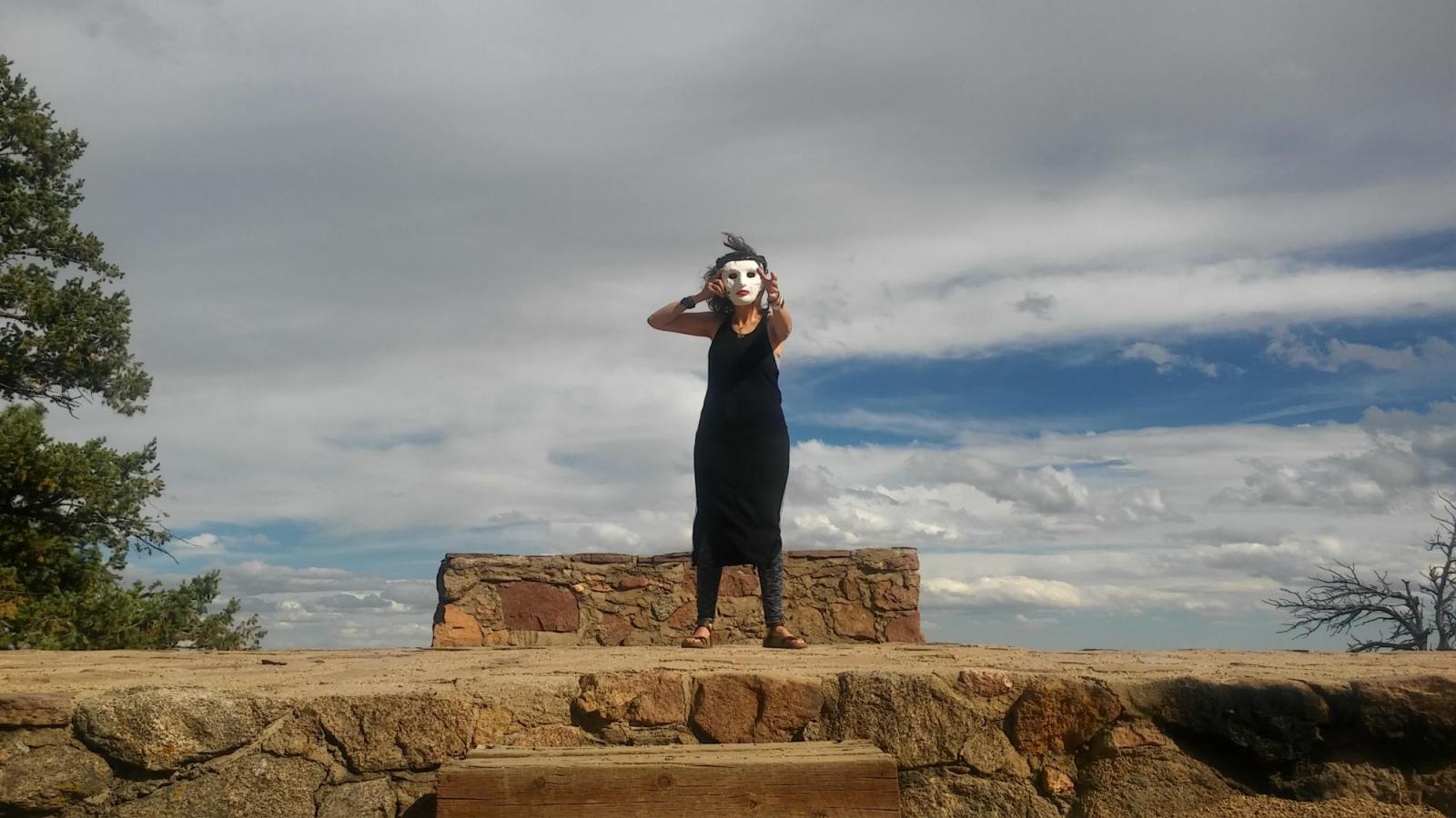 A masked performer reaches out from the top of a stone landing