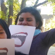 Fahmy holding paper sign with open mouth on it in front of her face