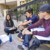 students sitting in circle talking while holding paper 