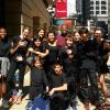 Cast of 8 students facing front outside the Goodman Theatre in NY