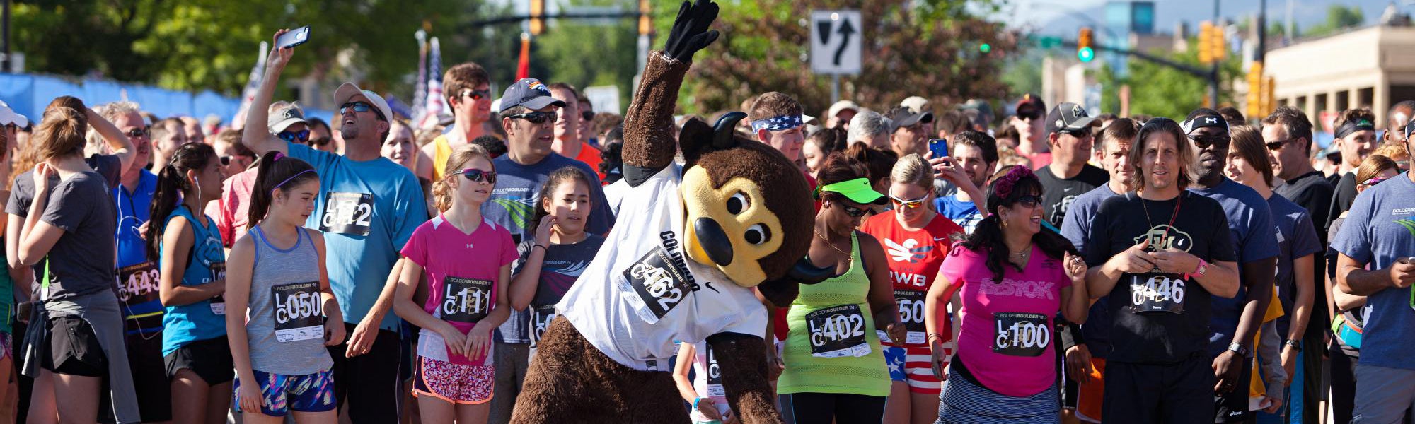 Chip stretching with other runners at the start line of the BolderBoulder