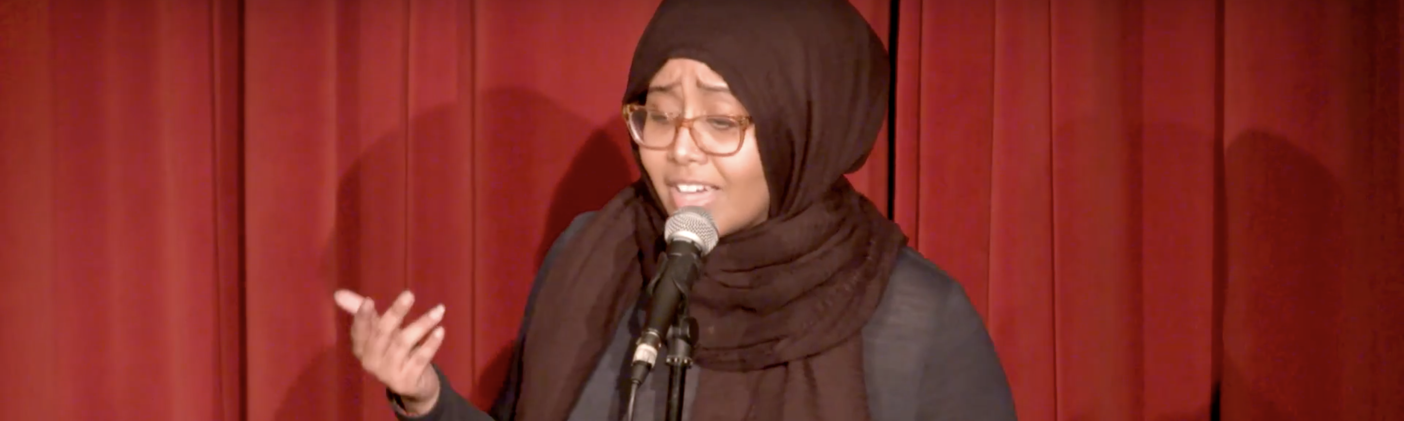 woman in a hijab speaking in front of a microphone