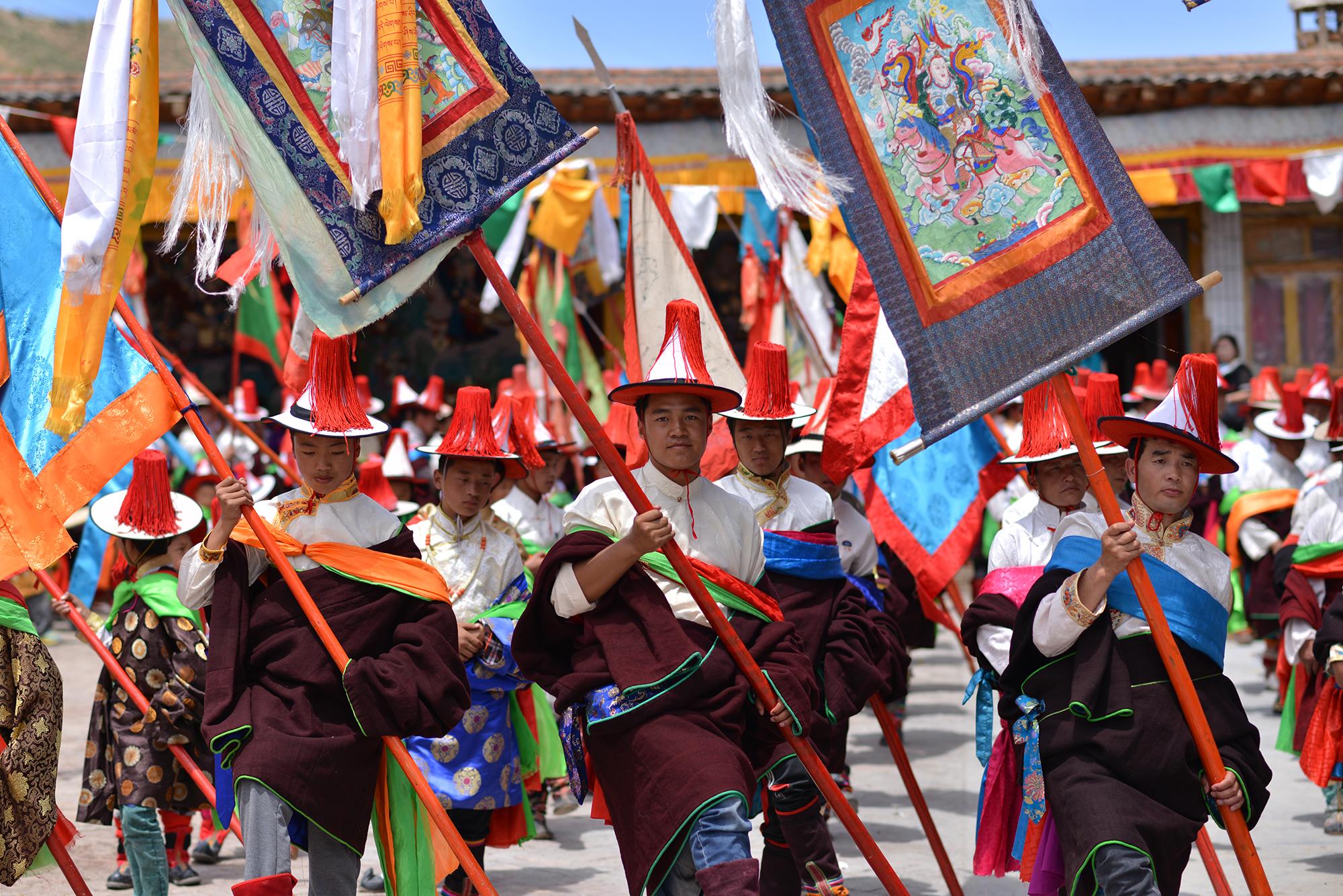 Wey La (be lha བེ་ལྷ) begins the final day of Lurol. Men march in the temple courtyard holding flags, spears, and paintings of deities.