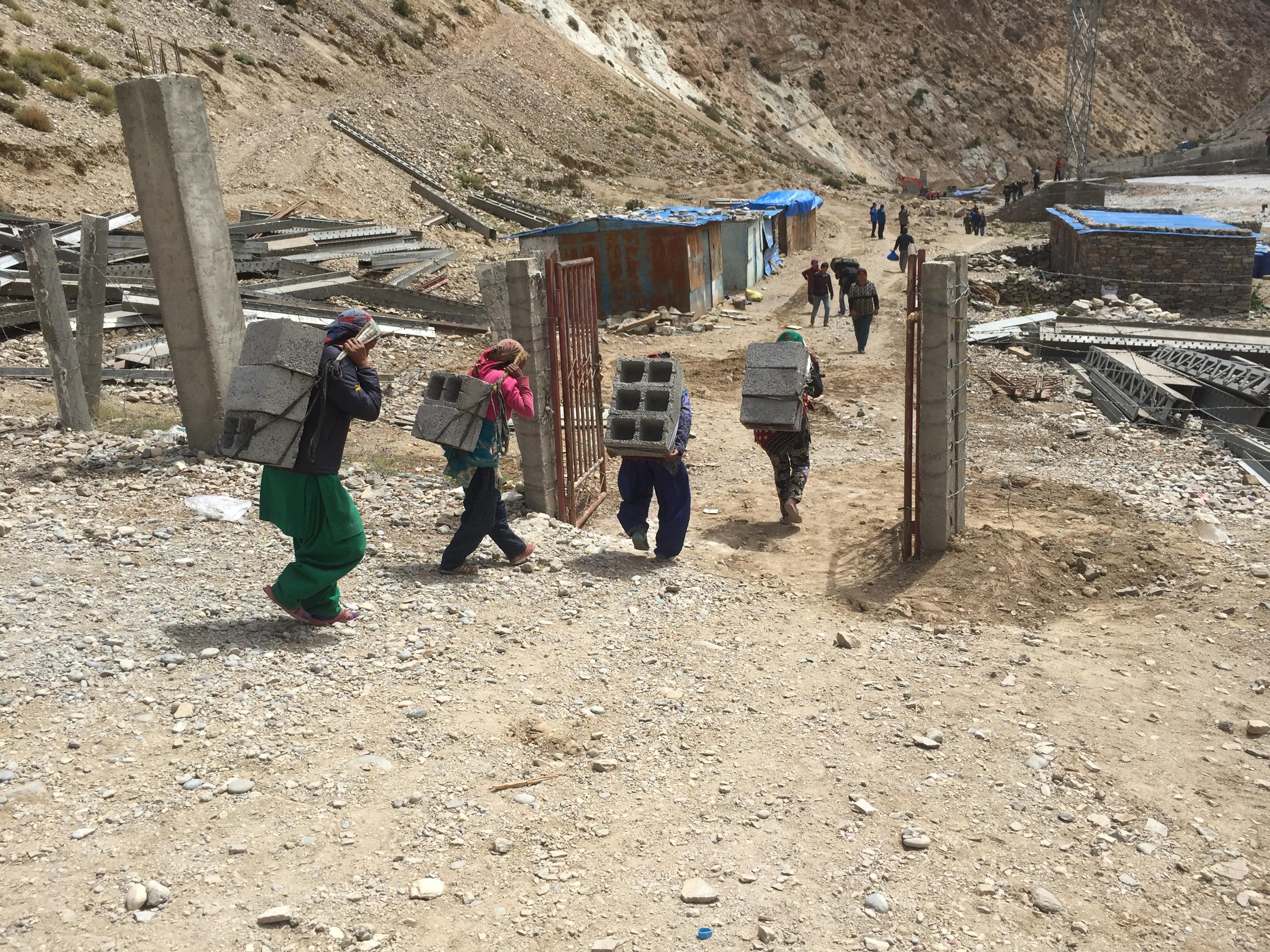 women carrying construction materials across the border