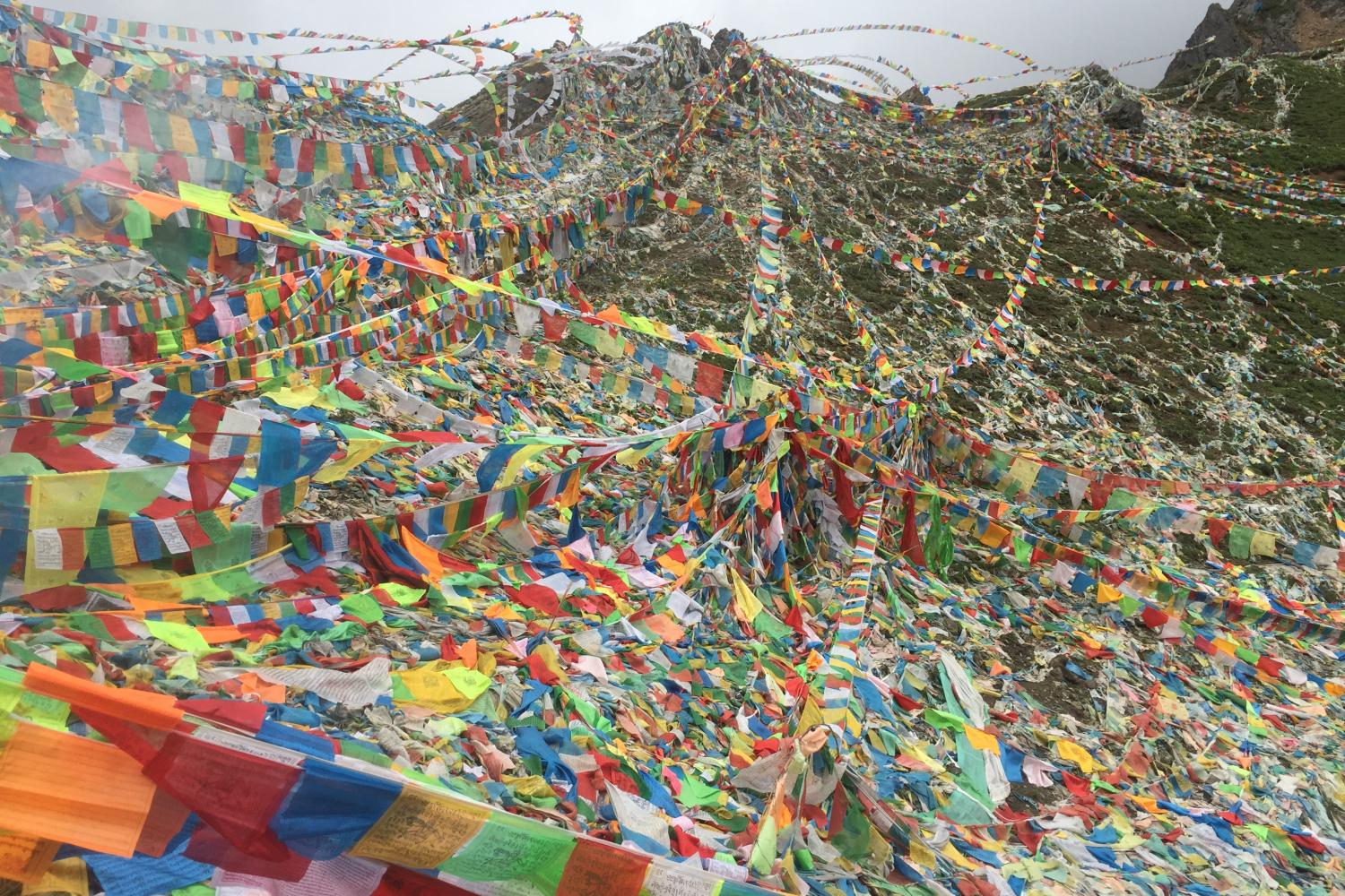 Prayer flags at the top of Dokela. In addition to the standard five colored prayer flags, there are many white prayer flags printed simply with Om mani padme hum, and on which a deceased person’s name is written.