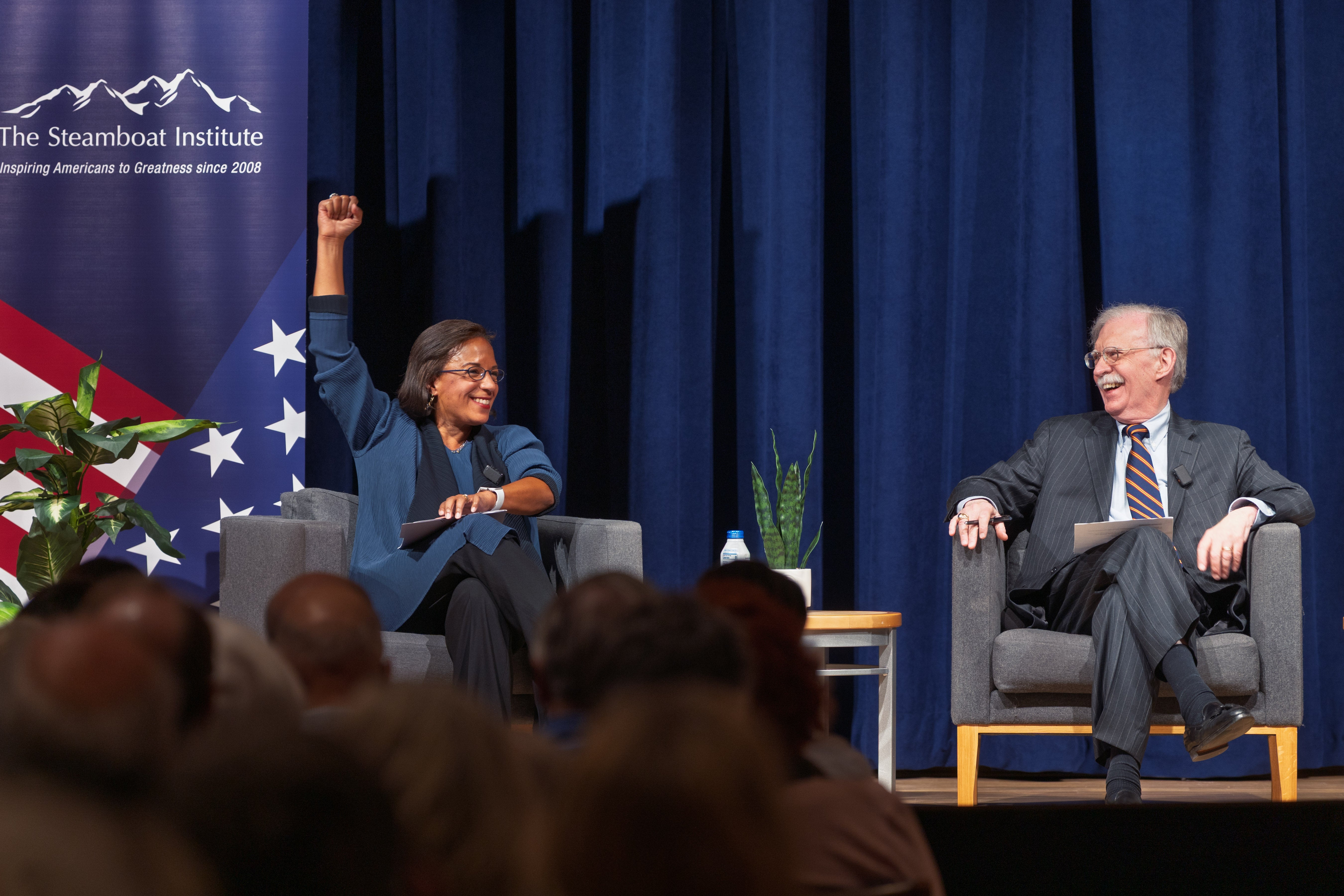 Susan Rice cheers as she and her debate counterpart John Bolton make their introductions