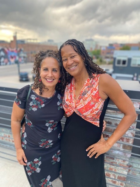 Suzette Malveaux, left, and Catherine Smith, right, pose in front of the Denver skyline