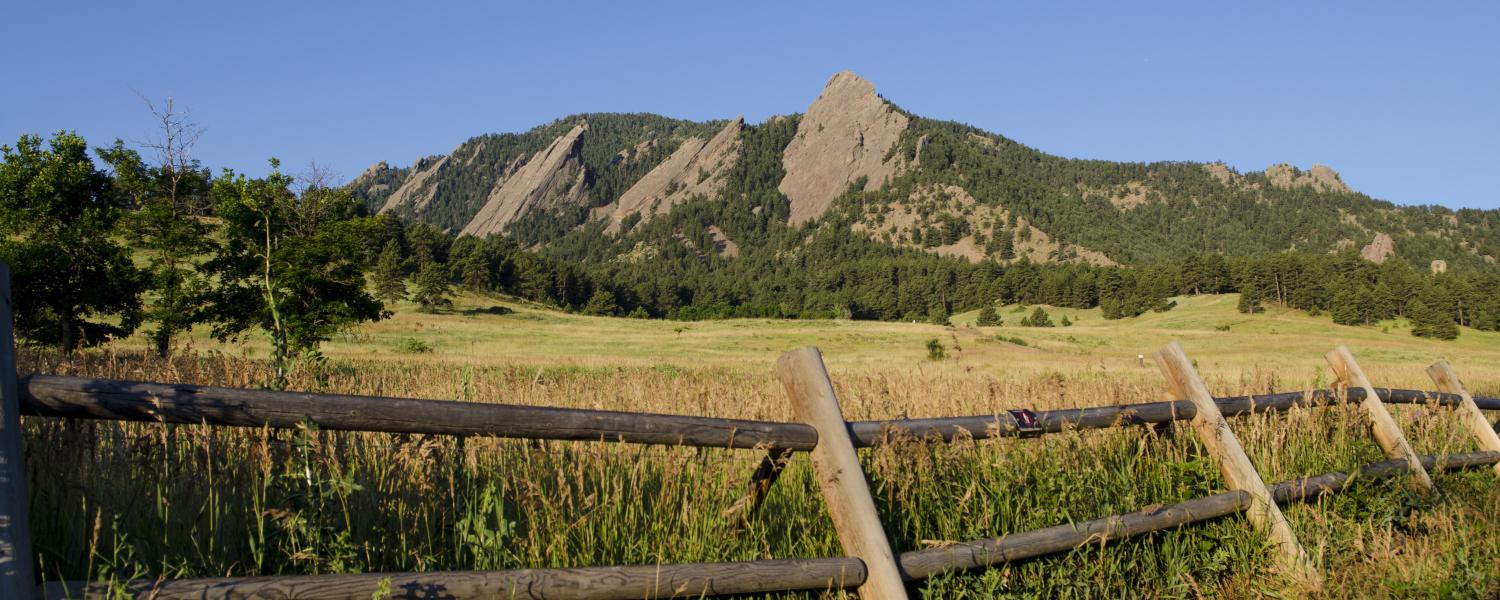 Wooden fence, green field and Flatirons