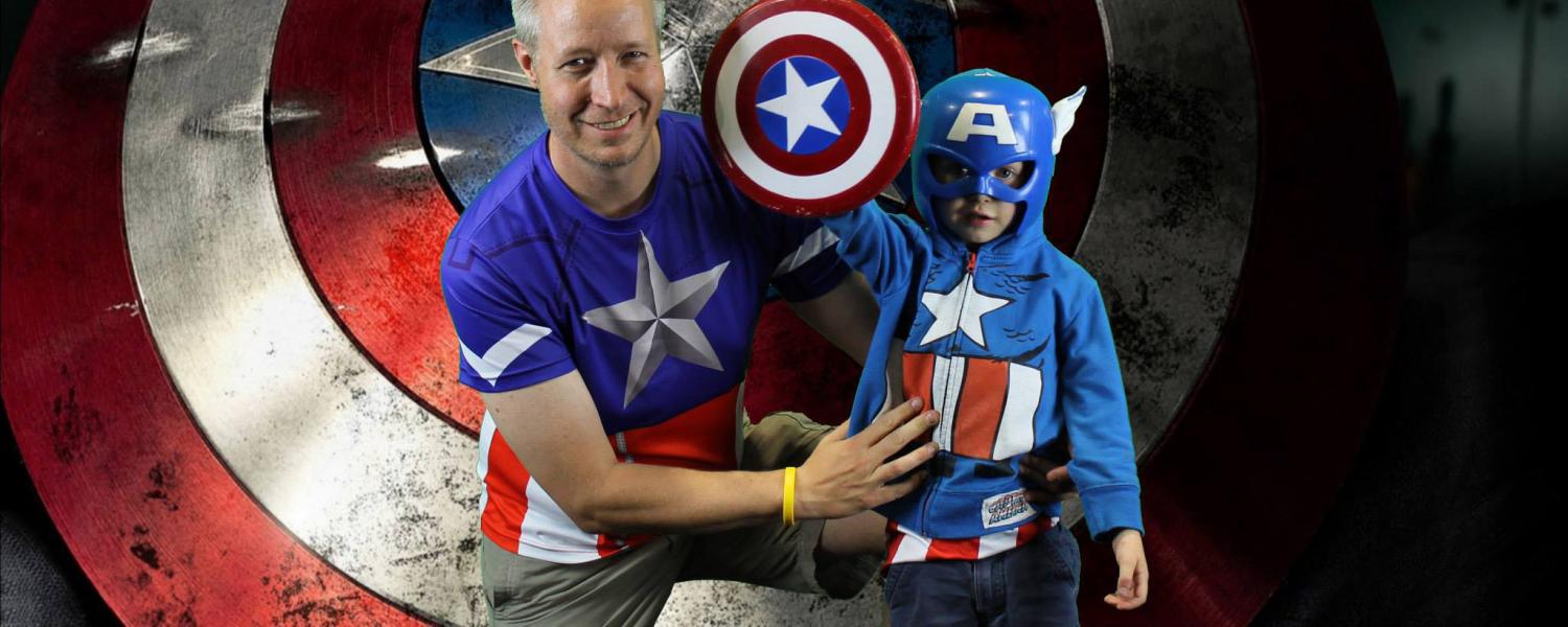 Rick Stevens and his son, Peter, stand in front of the Captain America shield at Denver Comic Con.