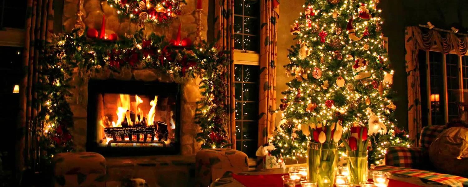 Brightly-lit Christmas tree with a warm fire in the fireplace