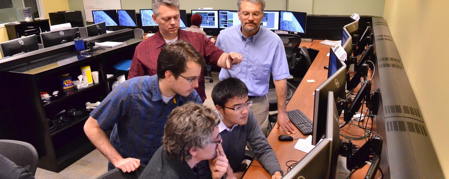 Group huddles around computer monitor