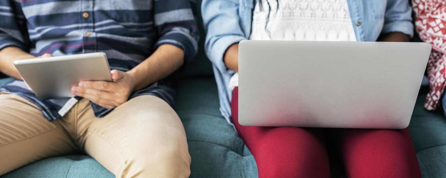 Students sit next to each other on tablet, laptop