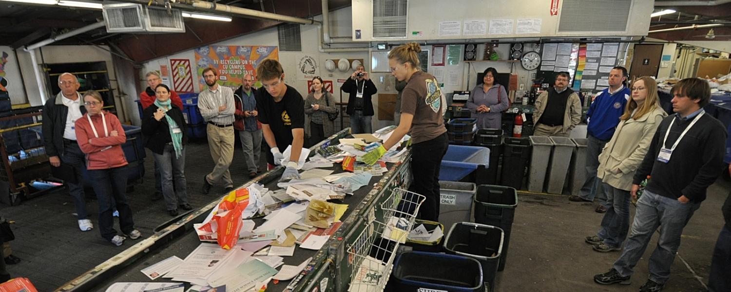 People observe the recycling sorting line during a sustainability tour