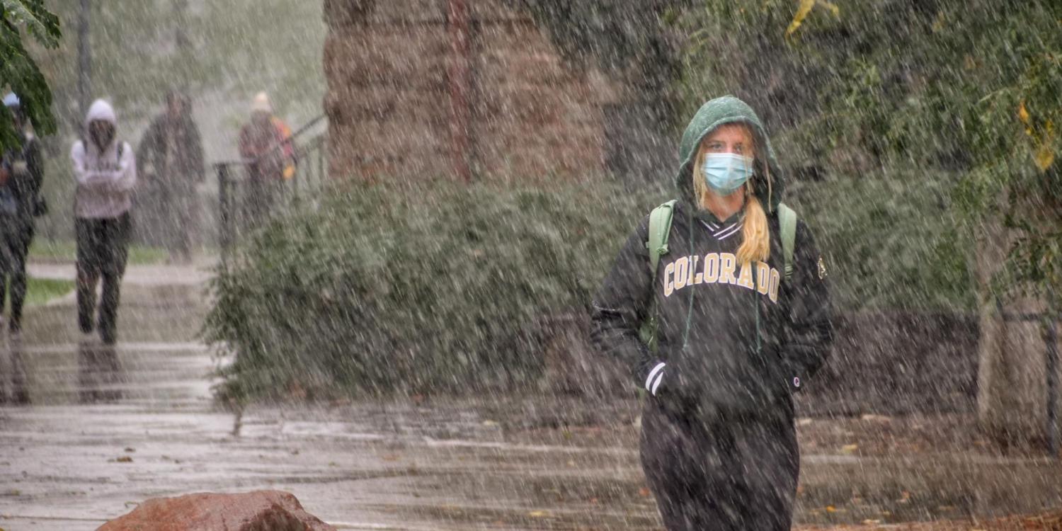 A student walking through the snow on the CU Boulder campus