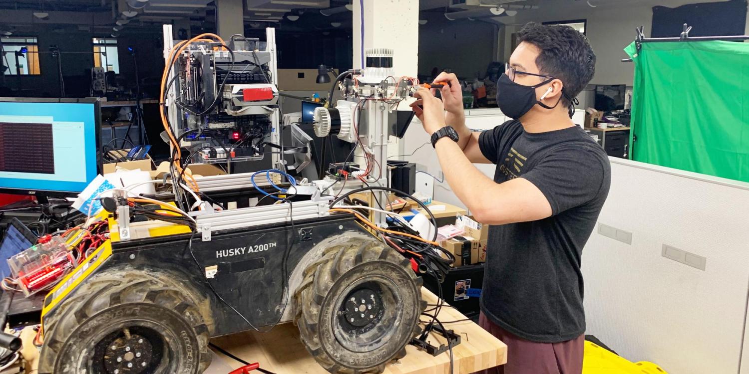 A member of a robotics research team working in a lab after a return to on-campus research