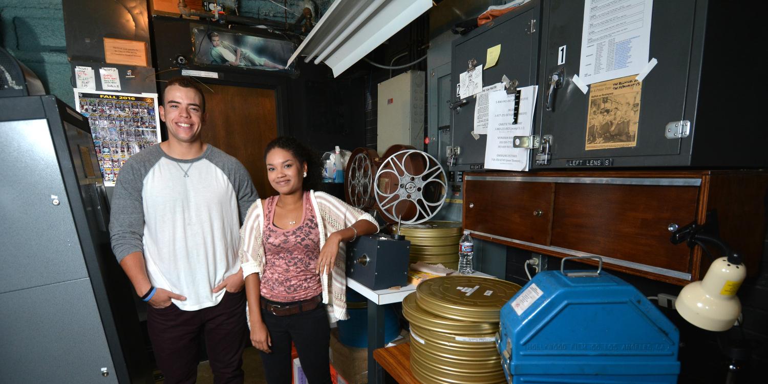 Adam Elbeck and Melina Dabney pose in the CU Boulder film lab with stacks of movie reels