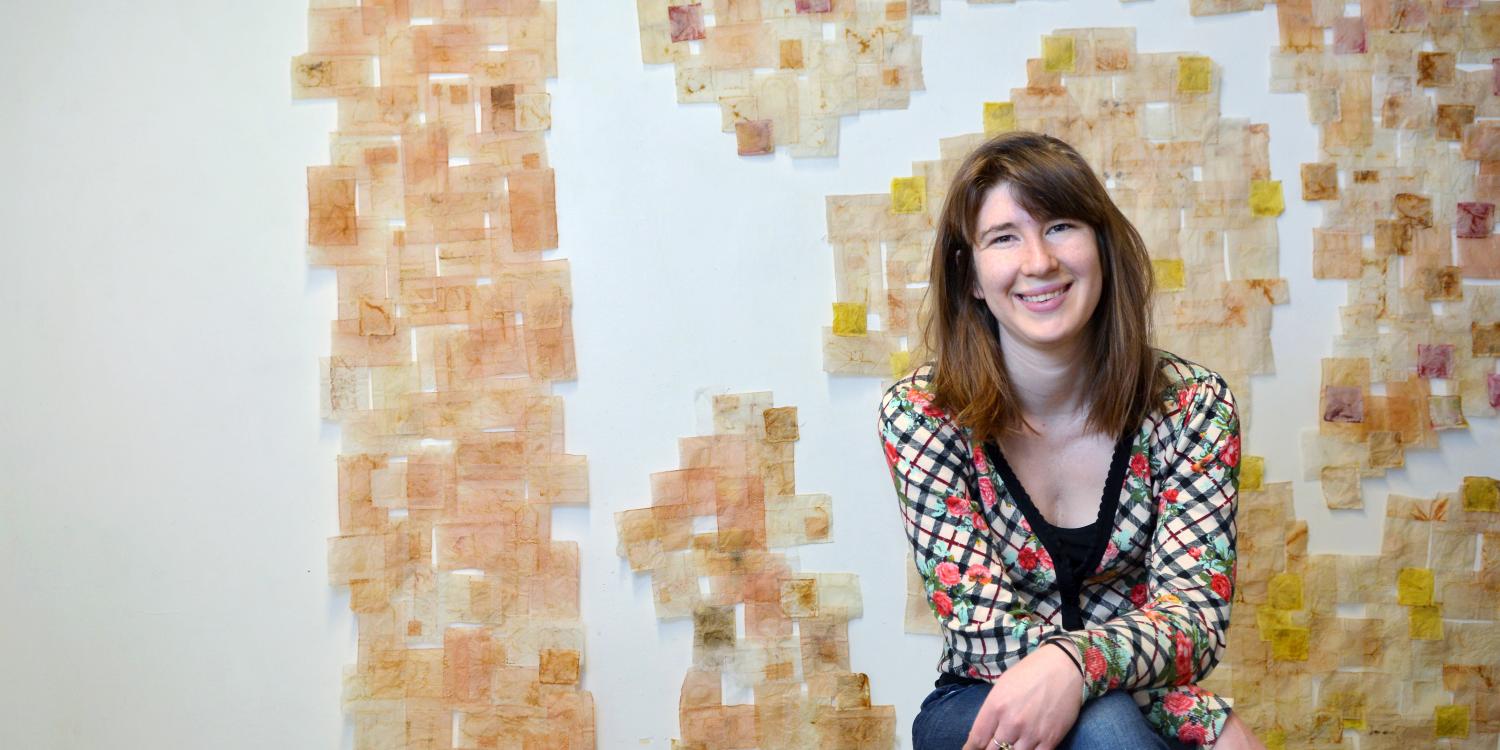 Ariana Kolins sits in front of a wall covered in used, empty tea bags