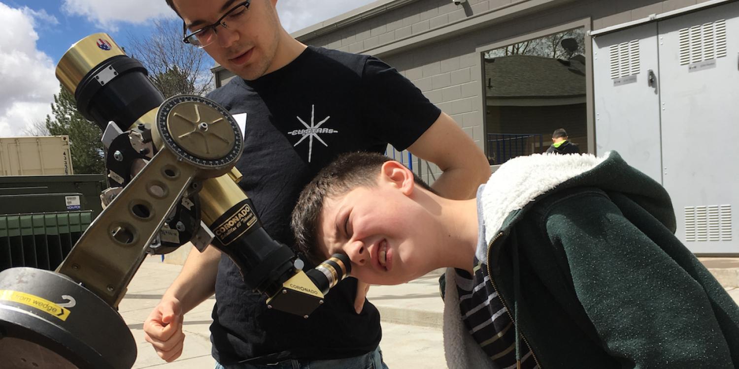 CU-STARs student volunteer helps child look through telescope
