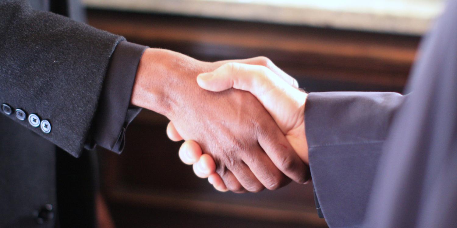 Black woman and white man shake hands