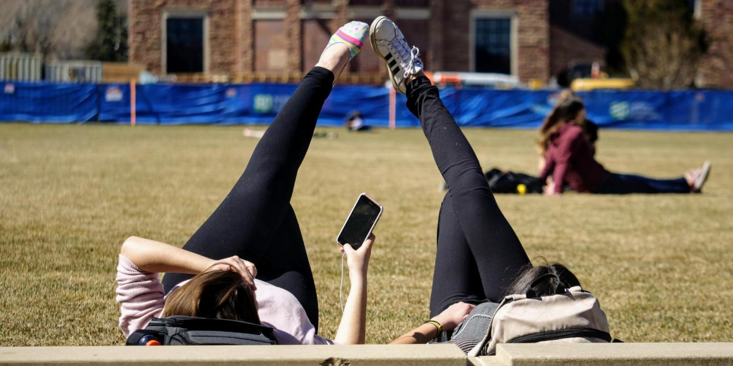 Two students lying in the grass of Farrand Field on the first day of spring