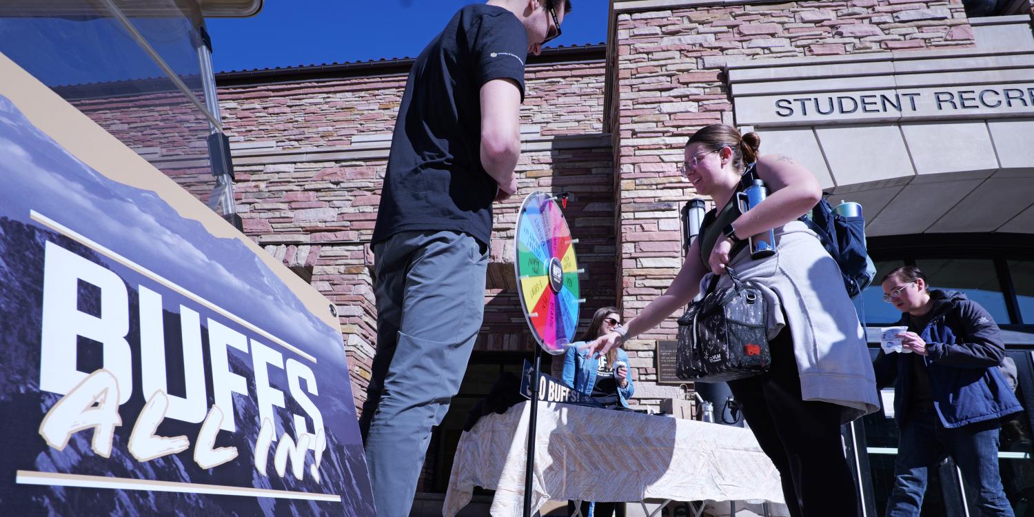People gather at a Buff All In promo table outside The Rec and spin a colorful prize wheel. (Photo by Casey A. Cass/University of Colorado)