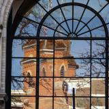 A reflection of Old Main in an arched window on campus.