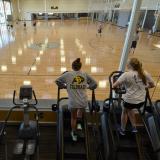 Students on ellipticals and stair climbers overlooking basketball courts at The Rec