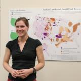 Grad student poses for photo in front of her research visualization board
