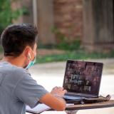 student joins virtual event on laptop outside