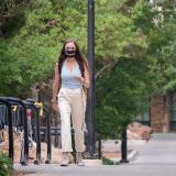 Student walking on campus while wearing a mask