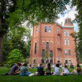 Classmates sitting in a circle in the grass in front of Old Main