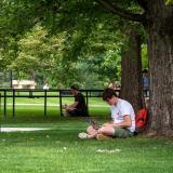 student sitting against tree studying