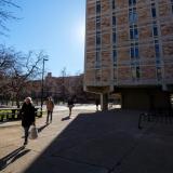 People walk in front of a building on the CU Boulder campus