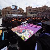 Graduates sit on Folsom Field during commencement ceremony